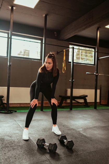 Jovem esportiva em roupas esportivas cansada e fazer uma pausa na academia