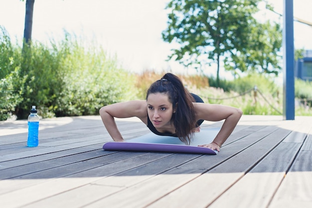 Jovem esportiva faz exercícios de ioga com tapete de ioga no conceito de estilo de vida ativo ao ar livre do parque