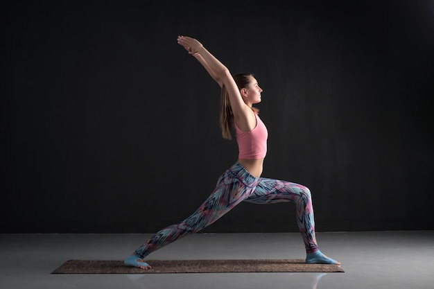 Jovem esportiva praticando guerreiro virabhadrasana foto de estúdio