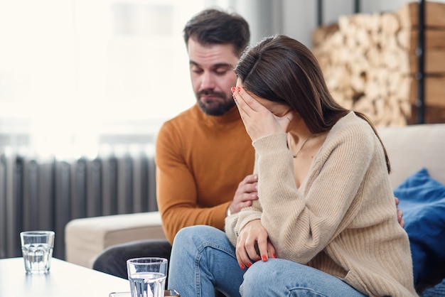 Jovem esposa amorosa, apoiando o marido deprimido durante a sessão de psicoterapia com conselheiro, espaço livre