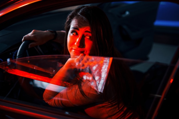 Jovem está dentro de um automóvel moderno novo com iluminação vermelha.