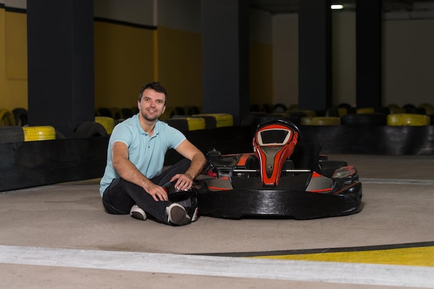 Jovem está dirigindo o carro GoKart com velocidade em uma pista de corrida de playground Go Kart é um esporte a motor de lazer popular