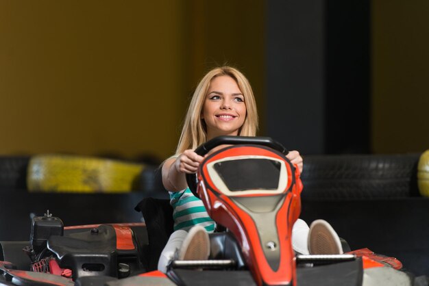 Jovem está dirigindo um carro GoKart com velocidade em uma pista de corrida de playground Go Kart é um esporte a motor de lazer popular