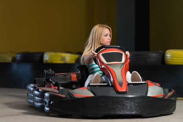 Jovem está dirigindo um carro GoKart com velocidade em uma pista de corrida de playground Go Kart é um esporte a motor de lazer popular