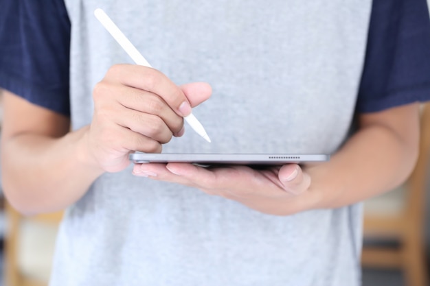 Jovem está escrevendo no tablet por lápis branco