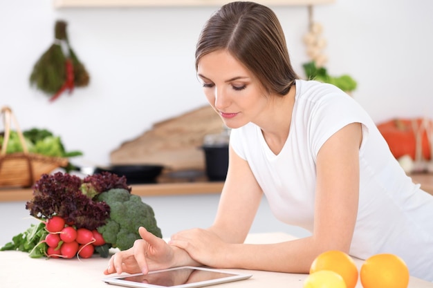 Jovem está fazendo compras on-line por computador tablet e cartão de crédito