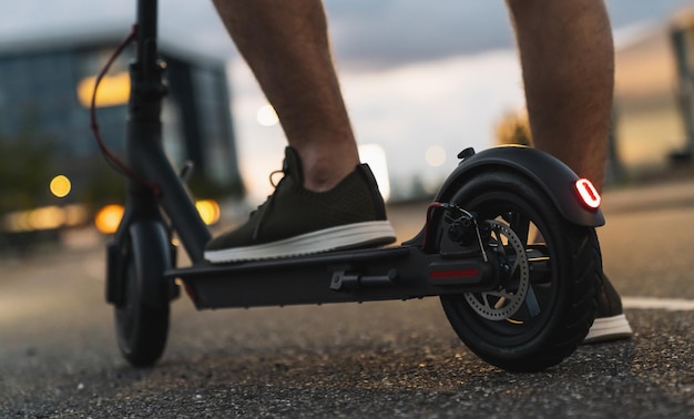 Jovem está pronto para descobrir a cidade urbana à noite com scooter elétrico ou escooter Imagem do conceito de transporte urbano elétrico