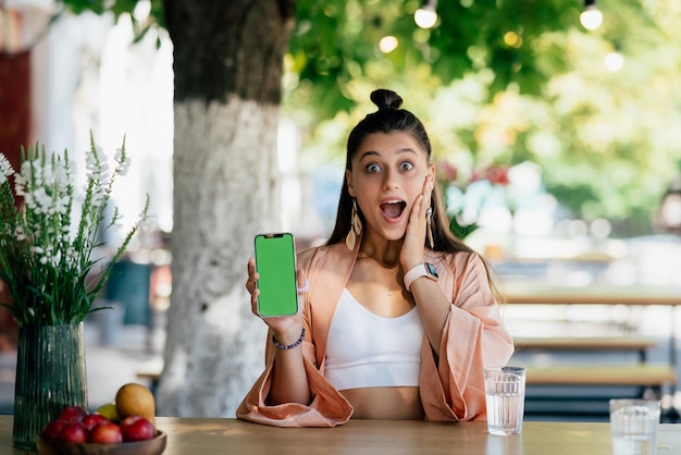 Jovem está segurando um smartphone com uma tela verde