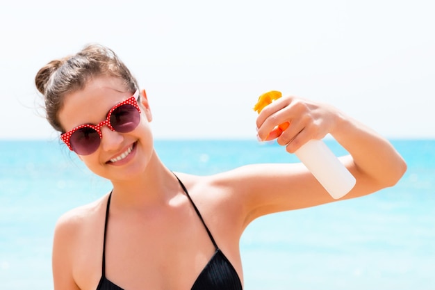 Jovem está segurando uma garrafa de protetor solar para o corpo no fundo do mar