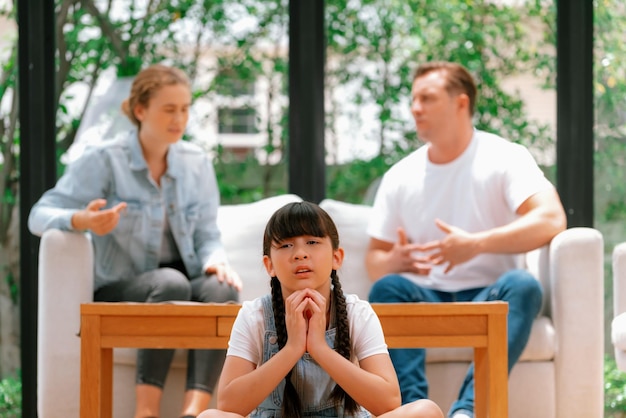 Jovem estressada e infeliz chorando e presa no meio da tensão pela discussão dos pais na sala de estar Estilo de vida doméstico pouco saudável e infância traumática evoluem para depressão Synchronos