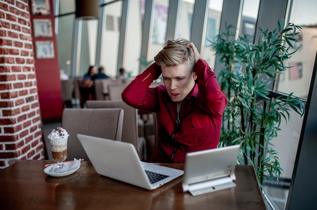 Jovem estressado trabalhando em um café