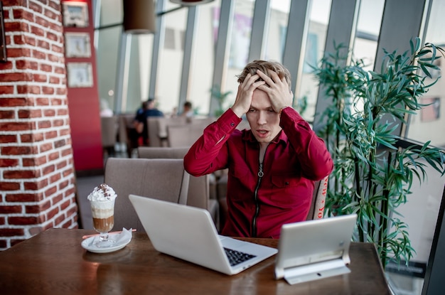 Jovem estressado trabalhando em um café