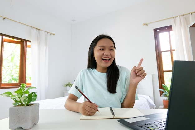 Jovem estudando com laptop no quarto aprendendo em casa