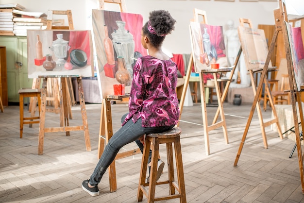 Jovem estudante africana pintando naturezas mortas pintando no estúdio