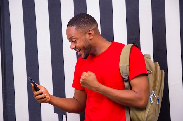 Jovem estudante africano se sentindo animado enquanto opera seu celular