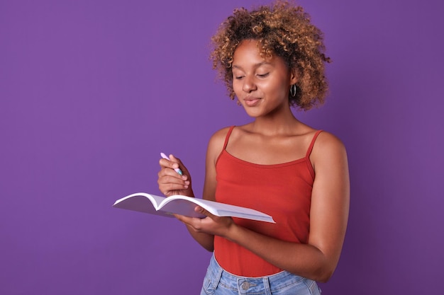 Foto jovem estudante afro-americana usa pasta de trabalho e canetas em estúdio