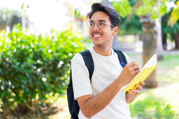 Jovem estudante ao ar livre segurando um caderno