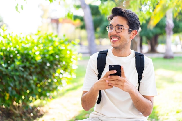 Jovem estudante ao ar livre usando telefone celular