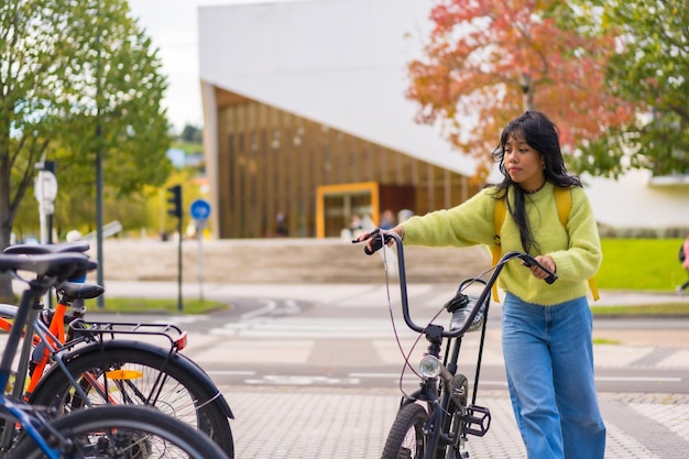 Foto jovem estudante asiática estacionando a bicicleta no campus universitário vida saudável e verde