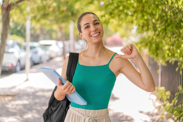 Foto jovem estudante bonita ao ar livre, orgulhosa e satisfeita