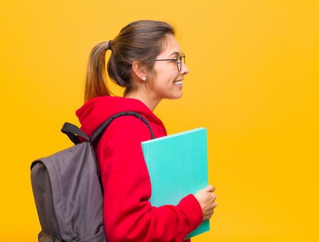 Jovem estudante bonita na vista de perfil, olhando para copiar o espaço à frente, pensando, imaginando ou sonhando acordado