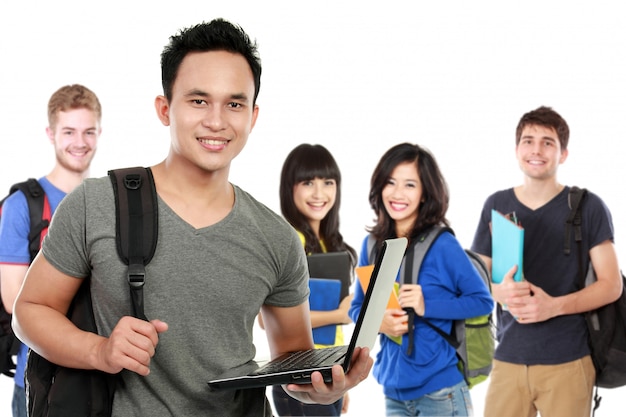 Jovem estudante bonito com laptop e amigos ao fundo