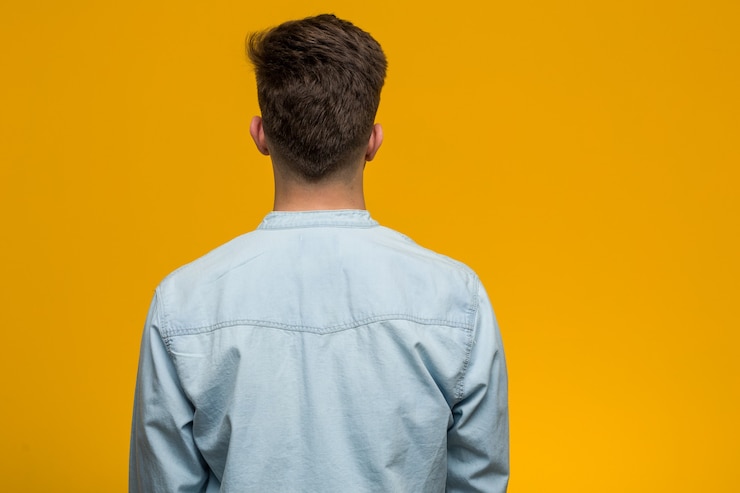 Foto jovem estudante bonito vestindo uma camisa jeans por trás, olhando para trás.