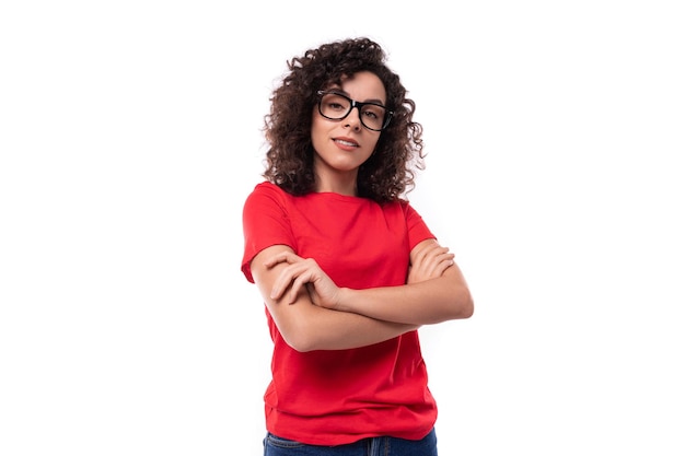 Foto jovem estudante brunete encaracolada ativa vestida com uma camiseta vermelha básica com maquete impressa