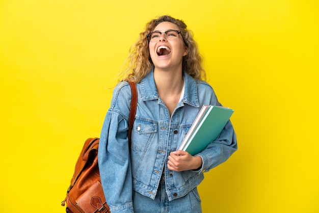 Foto jovem estudante caucasiana isolada em um fundo amarelo rindo