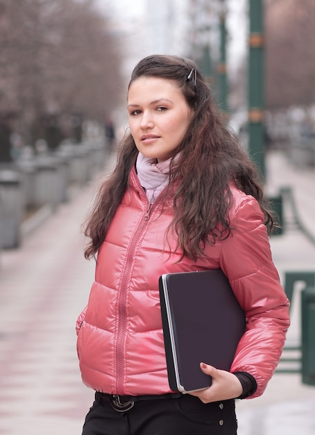 Jovem estudante com laptop em pé na rua da cidade