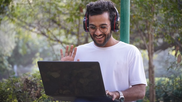 Jovem estudante com laptop em videochamada dizendo olá - cara com laptop