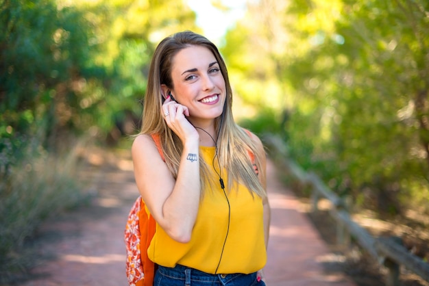 Jovem estudante com mochila em um parque de ouvir música