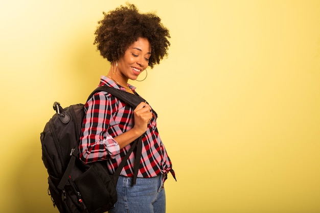 Foto jovem estudante com mochila nas costas em fundo amarelo