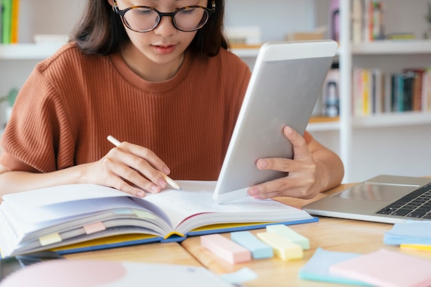 Jovem estudante de colagem usando computador e dispositivo móvel, estudando online.