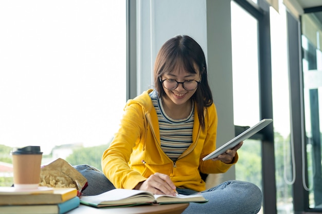 Jovem estudante de colagem usando o computador e o dispositivo móvel, estudando on-line.