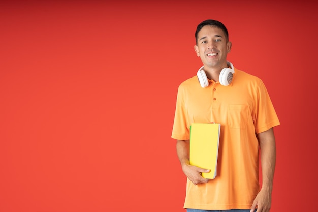 Jovem estudante do sexo masculino posando sorrindo com seus notebooks e fones de ouvido