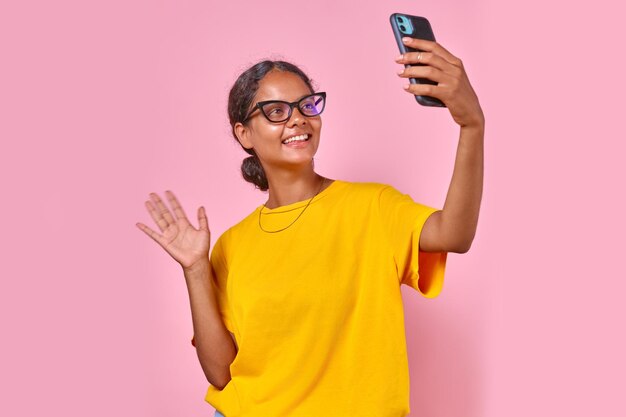 Jovem estudante indiana feliz segurando o telefone e agitando a mão está no estúdio