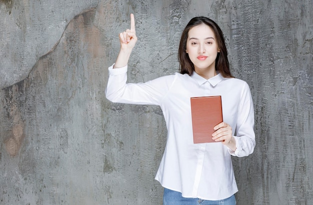 Jovem estudante ou professor com livro de literatura apontando. foto de alta qualidade