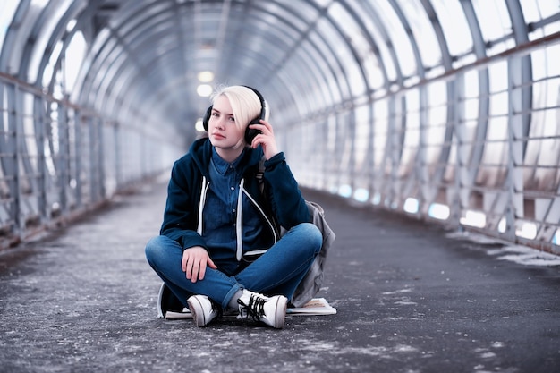 Jovem estudante ouvindo música com fones de ouvido grandes no túnel do metrô