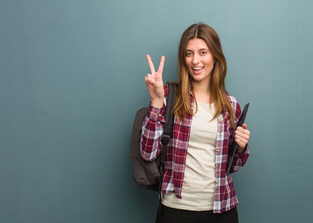 Jovem estudante russa mulher divertida e feliz fazendo um gesto de vitória