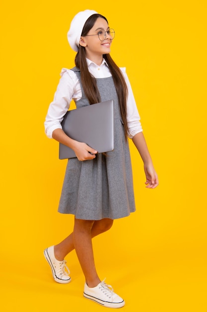 Jovem estudante segura computador Aluno engraçado com laptop isolado em fundo amarelo De volta à escola Rosto feliz emoções positivas e sorridentes de estudante adolescente