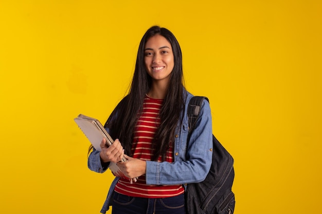 Jovem estudante segurando mochila e livros em foto de estúdio