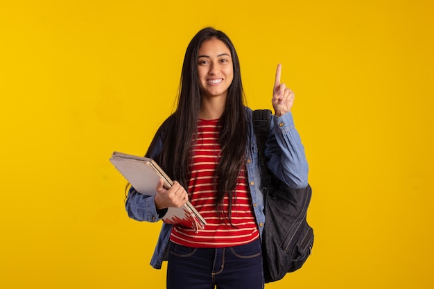 Jovem estudante segurando mochila e livros em foto de estúdio