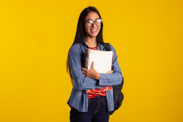 Jovem estudante segurando mochila e livros em foto de estúdio