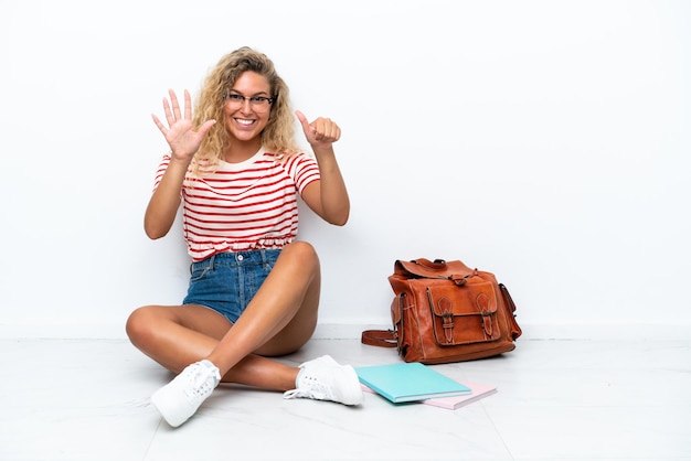 Jovem estudante sentada no chão, contando seis com os dedos