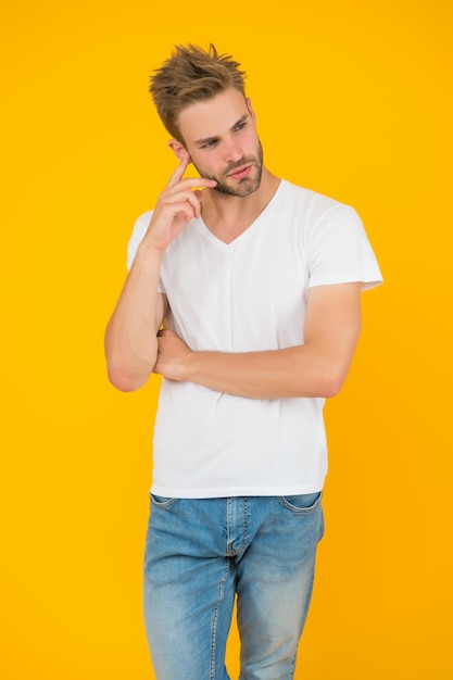 Jovem estudante sério conceito de barbearia cara bonito com luz homem sexy não barbeado em fundo amarelo estilo de beleza masculino carismático modelo de moda casual roupa de verão Extremamente bonito