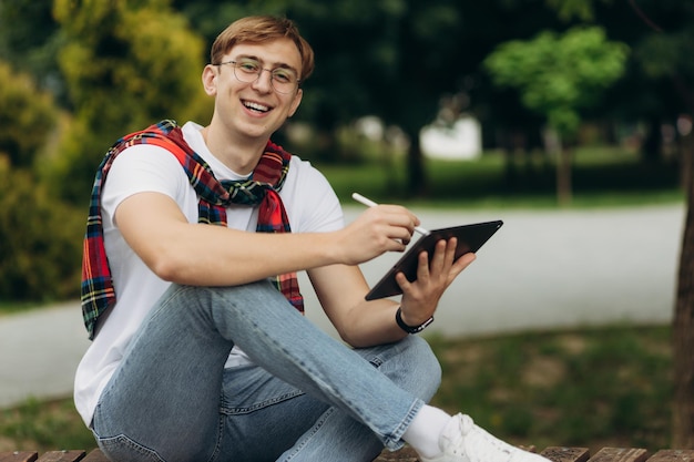 Jovem estudante sorridente ao ar livre com tablet O conceito de educação universitária