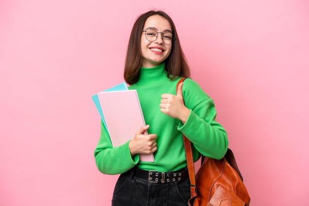 Jovem estudante ucraniana isolada em fundo rosa dando um polegar para cima gesto