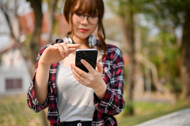 Jovem estudante universitária asiática usando seu telefone no parque do campus