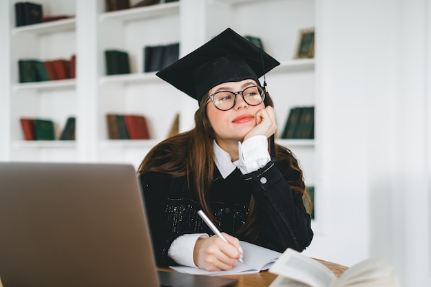 Jovem estudante universitária caucasiana pensativa com roupa de formatura